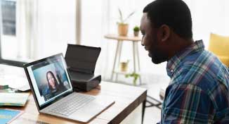 Imagen de  Man sitting infront of a laptop having a virtual interview with a lady on screen.